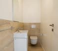 Bathroom with white vanity, toilet, and tiled walls and floor