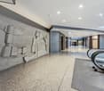 Concrete wall with abstract design, polished concrete floor, escalator, gray carpet, white ceiling with lights