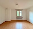 empty room with hardwood floors, white walls, small window, white radiator