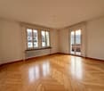 large room, white walls, wooden floor, radiator, sliding glass doors to balcony