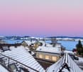 Houses with snow-covered roofs, a lake, and mountains in the background