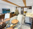 living room with wooden beams, Christmas tree, TV, wooden furniture, white chairs, glass table, couch, fireplace