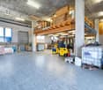 spacious warehouse, concrete floor, wooden mezzanine, industrial shelving, forklifts, storage boxes, window, door