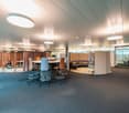 modern office space with round table, chairs, round couch, glass walls, carpet, lamps