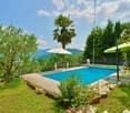 Swimming pool in the garden with view of the mountains, 2 statues, 2 umbrellas, plants and trees