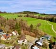Aerial view of a neighborhood with several houses, green fields, and trees.
