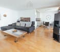 modern living room with grey sofa, coffee table, speaker, shelves, clock, dining table and chairs