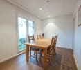 empty room, wooden table, chairs, glass door, parquet floor, white walls, picture on the wall
