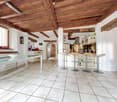 white tiles, glass table, island with bar stools, wooden beams ceiling, open kitchen