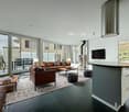 modern style, large windows, balcony, couches, coffee table, ottomans, television, fireplace
