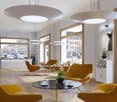 large windows, chandeliers, wood floors, yellow couches, round table, coffee, plants