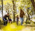 a family walking through a forest area, with tall trees and plants