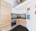 modern kitchen with wooden cabinets, black countertops, stainless steel appliances, tiled floor, decorative items on the wall