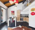 modern kitchen with dining area, wooden cabinets, white countertops, black tiled floor, large windows, balcony