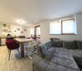 Open plan living room and kitchen, wooden table, gray sofa, kitchen appliances, dining chairs, floor lamp