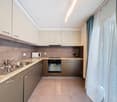 modern kitchen with white cabinets, granite countertops, stainless steel sink, built-in microwave, oven, dishwasher, and a faucet