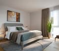 A bedroom with a bed, nightstands, a rug, a painting, a potted plant, and a chair.