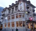 multi-story building, arched windows, balconies, storefront with displays, Swiss flag