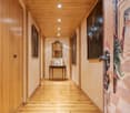 Wooden paneled hallway with a fireplace, artwork on the walls, and a wooden floor.