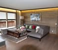 Spacious living room with wooden walls, large windows, gray sectional sofa, wooden coffee table, and artwork on the wall.