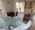 glass table, 4 white armchairs, couch, cabinet, balcony, floor windows