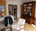 Dining area with table and chairs, bookcase, armchair, lamp, rug