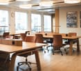 modern office room, long wooden desk, brown swivel chairs, large windows, wall clock, picture frames, wooden floor, lamps