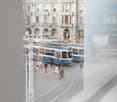 Outdoor view of a busy street with trams and people walking, large building in the background