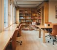 wooden furniture, leather chairs, glass windows, large bookshelf, table with swivel chairs, picture on wall