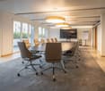 Meeting room with large oval table, leather chairs, large glass windows with city view, monitor
