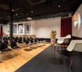 conference seating with black chairs, black floor in the front, white walls, projector screen, two armchairs, small table