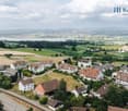 Aerial view of residential area, various sized houses, greenery, road, distant mountains