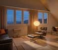 Leather sofa, leather armchair, ottoman, dining table, floor lamp, large windows, wooden floor, view of mountains