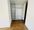 Empty room with a corner wardrobe, wooden floor, white walls.