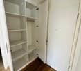 Empty wardrobe with hanging rod, several shelves, wooden floor