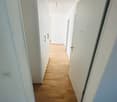 Wooden flooring, white walls, tall cabinets, hallway leads to another room