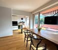 wooden floor, dining table, chairs, balcony, kitchen area, wall-mounted clock