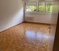 Empty room with parquet flooring, white walls, large window, and a white radiator.