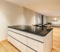 large kitchen island, black marble countertop, wooden flooring, modern interior