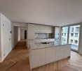 white cabinets, marble countertops, stainless steel sink, wooden floors, large windows, balcony with railings