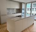 Kitchen with marble countertop, stainless steel sink, large windows leading to a balcony