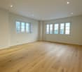 large empty room, wooden floor, white walls, recessed lighting, large windows