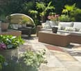 Stone patio, potted plants, sofa set with cushions, outdoor table, shade