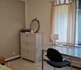 Bedroom: desk, chair, cabinet with mirror, radiator, bed, window with curtains