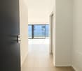 spacious hallway, large glass doors leading to balcony, tan tile flooring, white walls, large windows with view