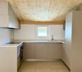 Modern kitchen, wooden ceiling, tiled floor, white cabinets, gas stove, oven, sink, window