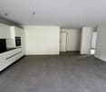 Empty room with tiled flooring, white walls, black counter top, white cabinets, open door leading to another room.