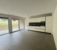 empty kitchen with sliding glass doors opening to balcony, tile flooring, white cabinetry, modern fixtures