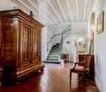 Wooden cabinet, vintage chair, hallway with staircase, tiled floor, picture frames