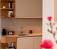 Kitchenette, undermount sink, countertops, wooden cabinets, countertop shelves, flowers in vase